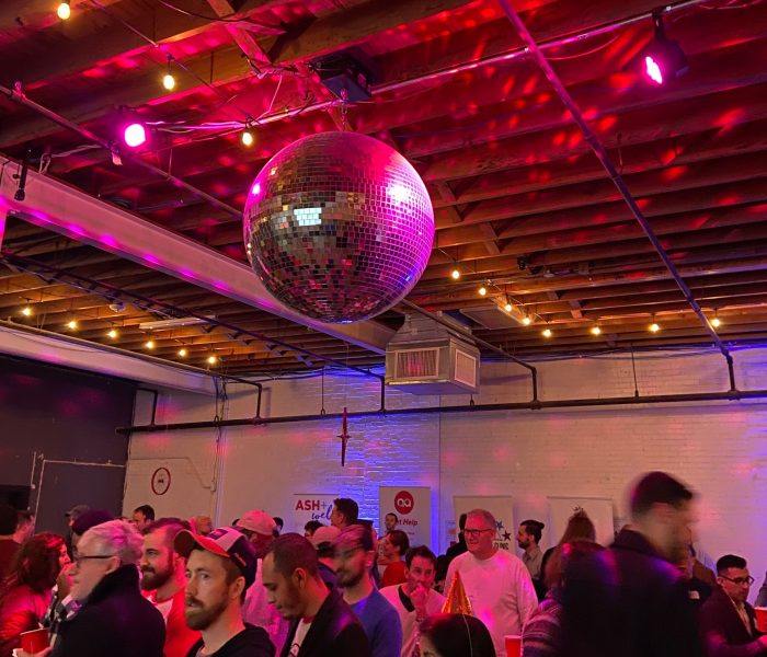 pre-pandemic party scene with a lot of people in a room and a big disco ball on the ceiling