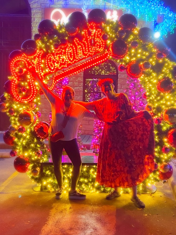 2 women standing in front of a giant lit up wreath