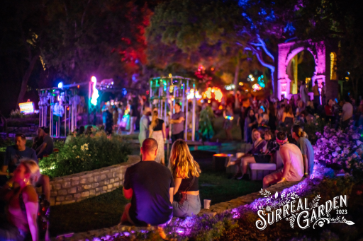 Photo of people sitting on a low wall with lit-up sculptures in the background
